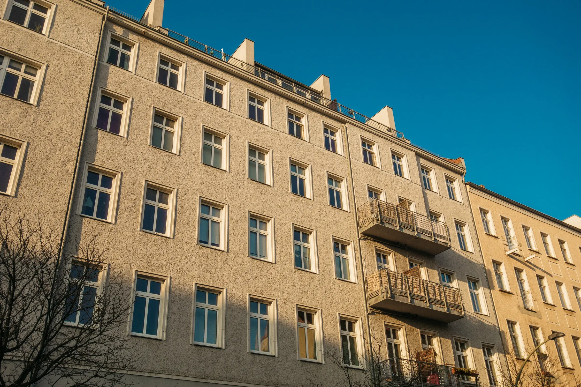 Wohngebäude mit Balkonen und symmetrischer Fassade unter blauem Himmel